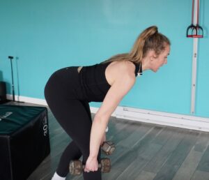 Dr. Chloe hinging over her right hip as she is doing a kickstand rdl for as a hip exercise which is also a functional exercise